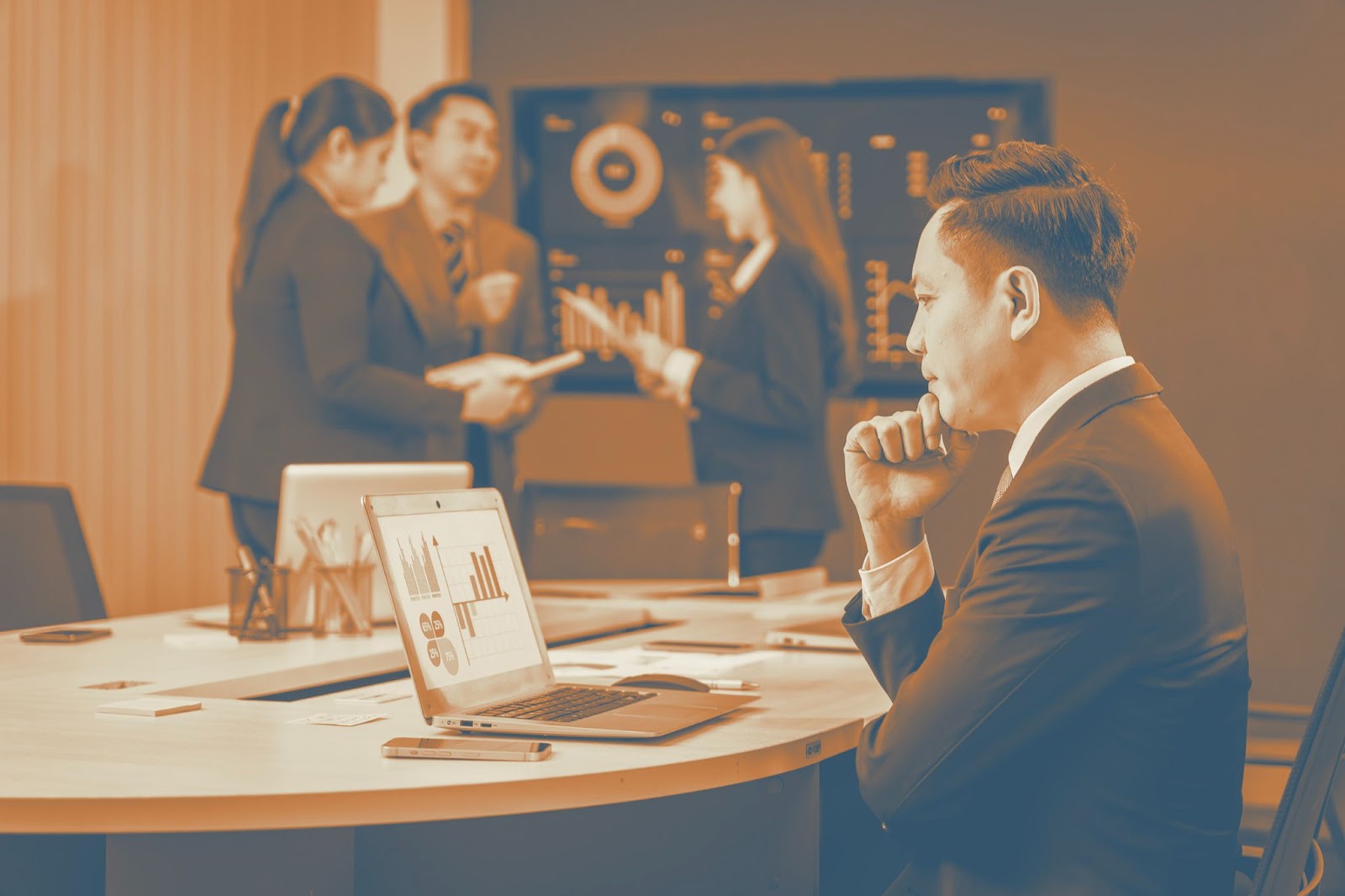 Business executive reviewing charts on a laptop during a conference room meeting with colleagues